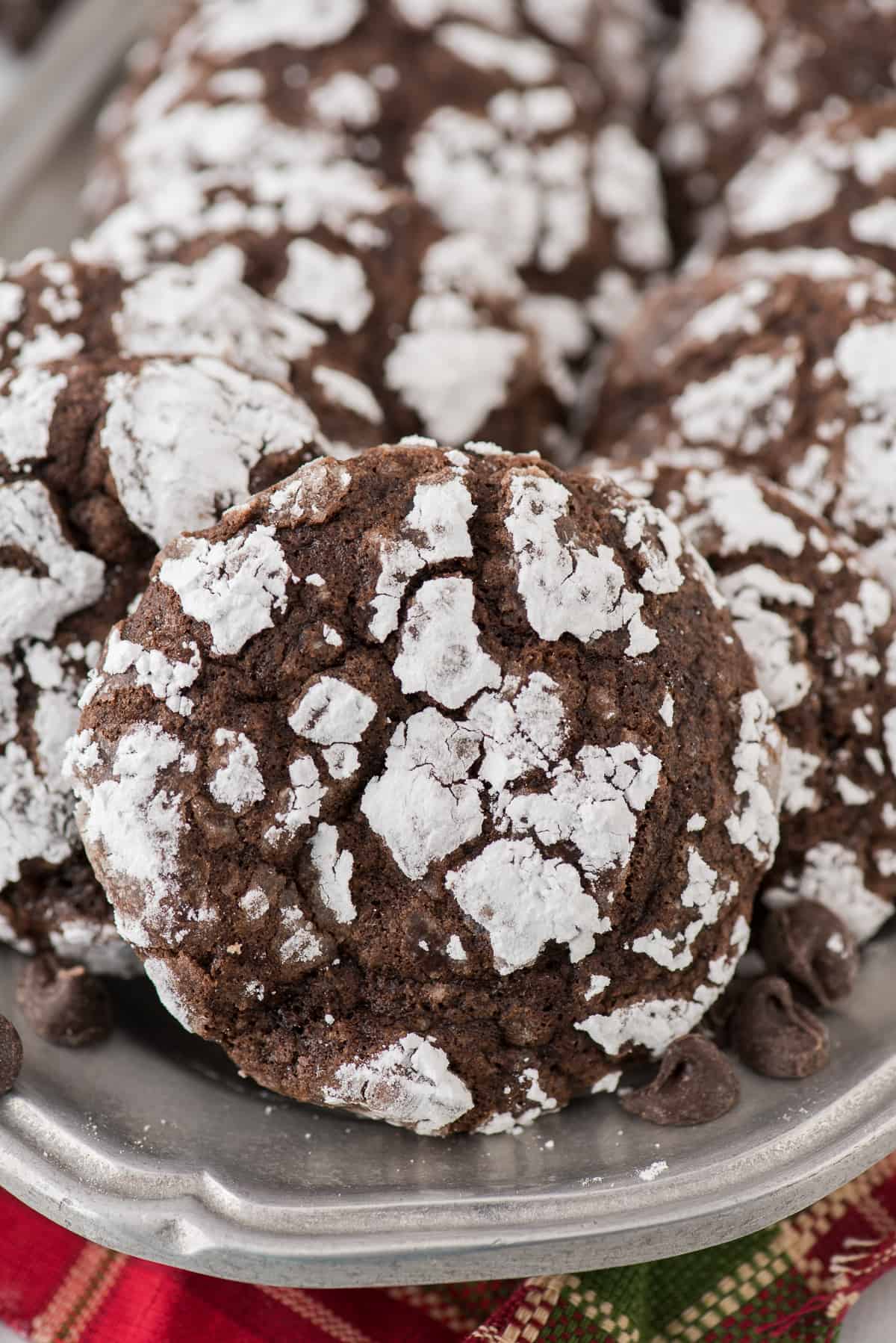 chocolate crinkle cookies rolled in powdered sugar on metal tray with red towel underneath