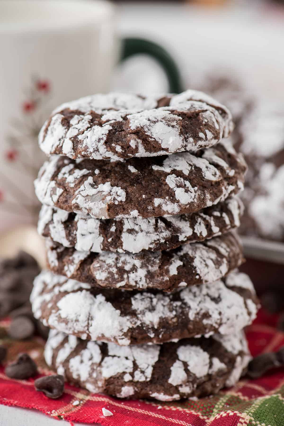 chocolate crinkle cookies rolled in powdered sugar stacked on a red towel