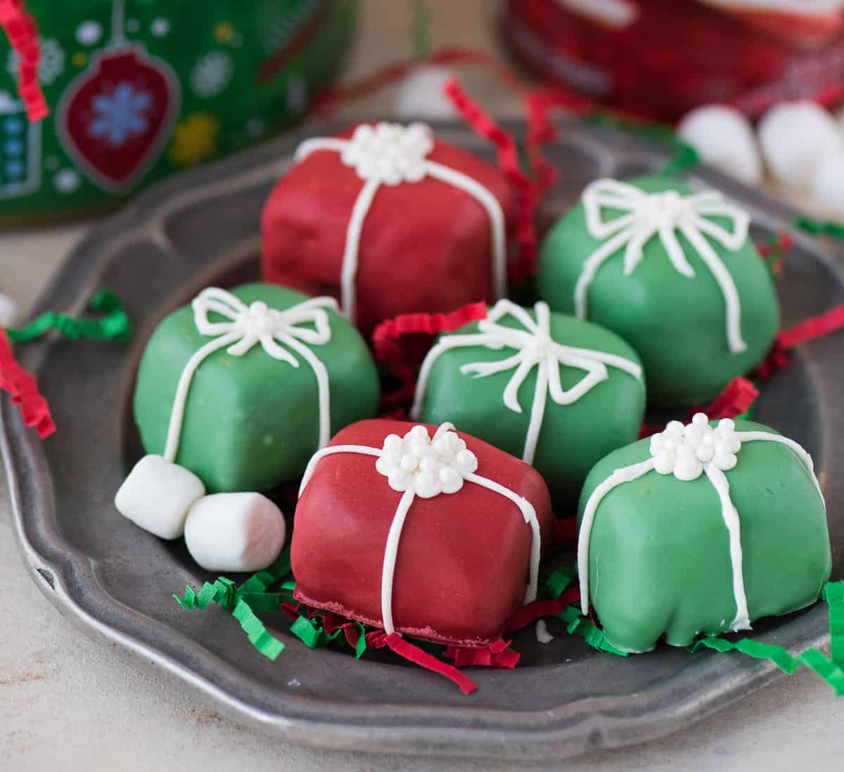 red and green oreo balls shaped as christmas presents with white bows on metal plate