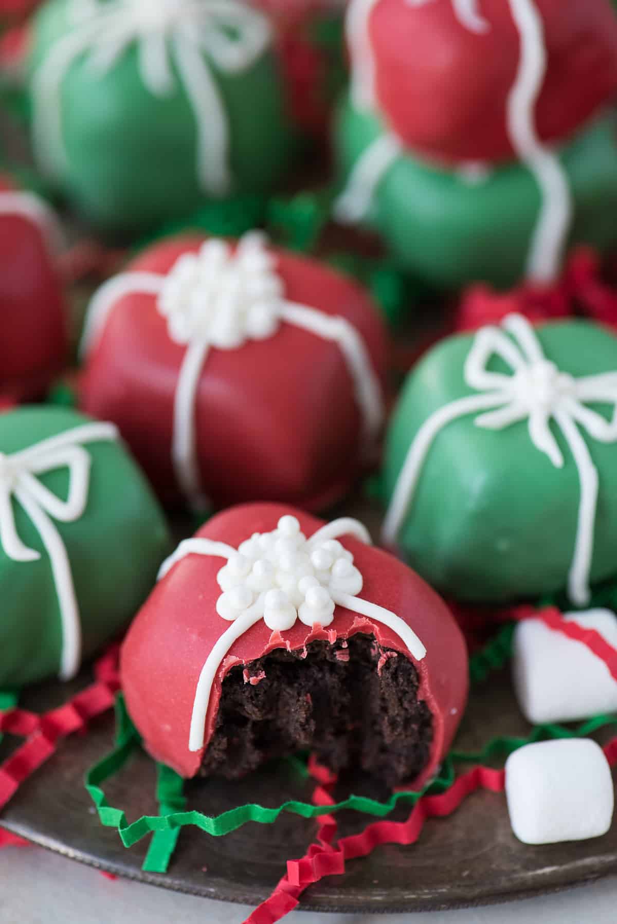 red and green oreo balls shaped as christmas presents with white bows on metal plate