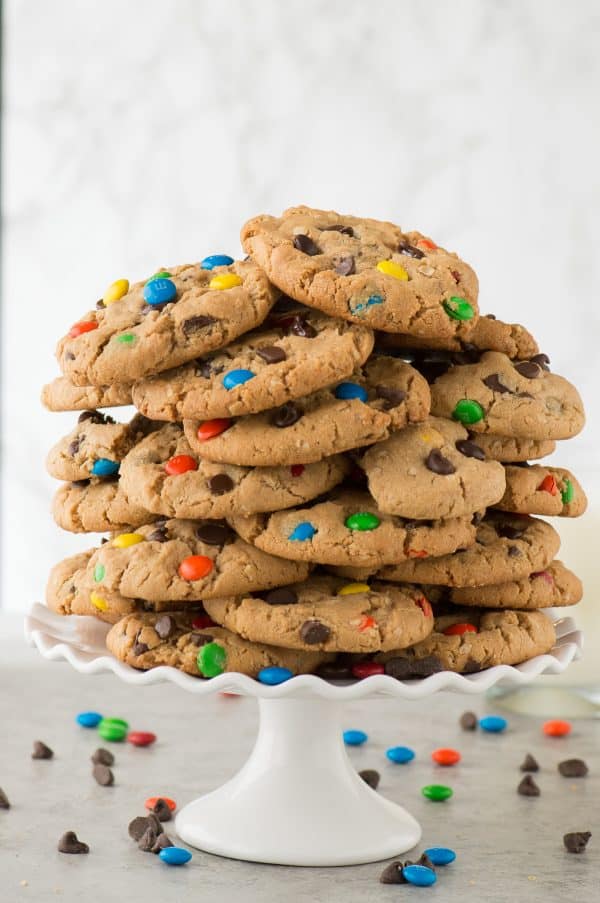 monster cookies in a giant stack on a white cake stand