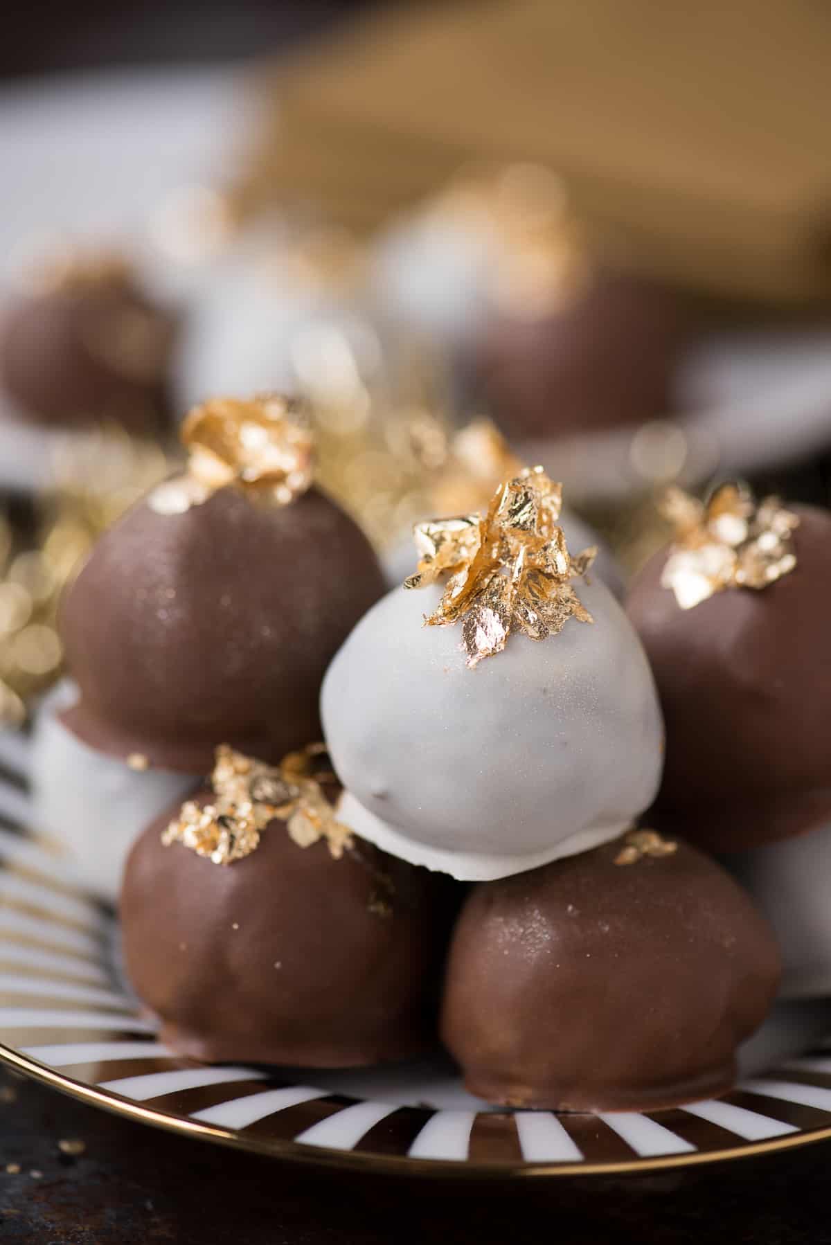 oreo balls displayed on gold striped plate with edible gold flakes on top