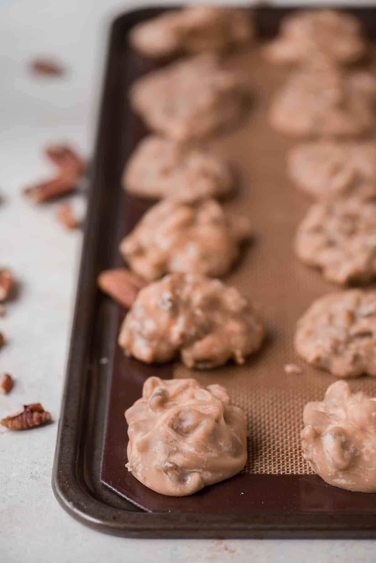 pecan pralines arranged in a grid on baking sheet