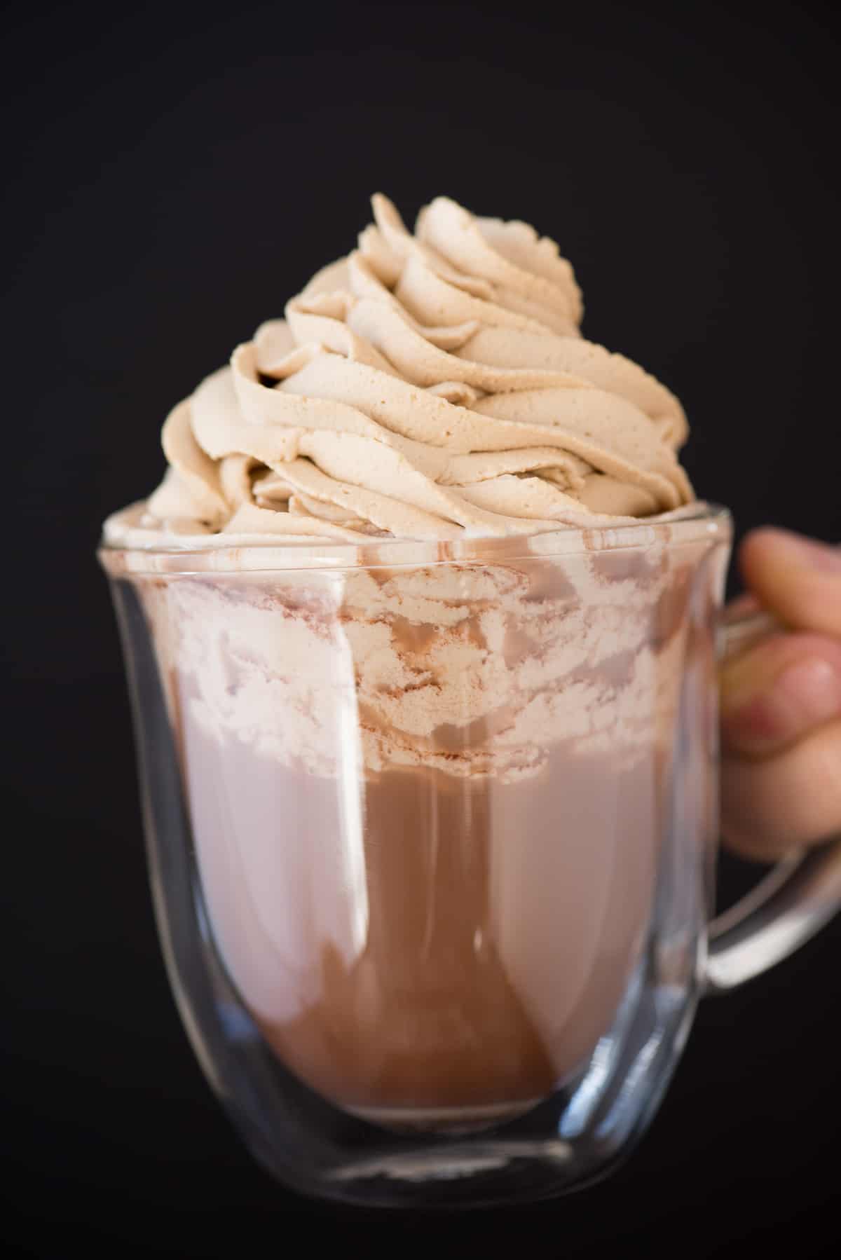coffee whipped cream piped on top of hot cocoa in clear mug