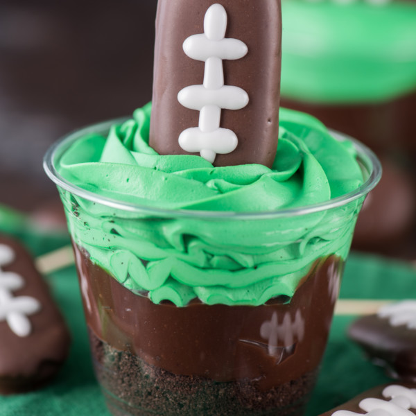 Easy Football themed dirt cup with bright green frosting and a football shaped cookie on top.