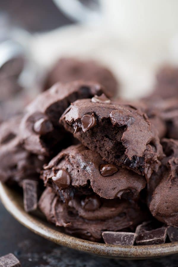 Healthier Dark Chocolate Coconut Oil Cookies - These are estimated to be 150 calories. I love that the recipe calls for ordinary ingredients, and no refined sugar, butter or oil! A bitten out of healthier dark chocolate coconut oil cookie on top of other cookies in a plate.