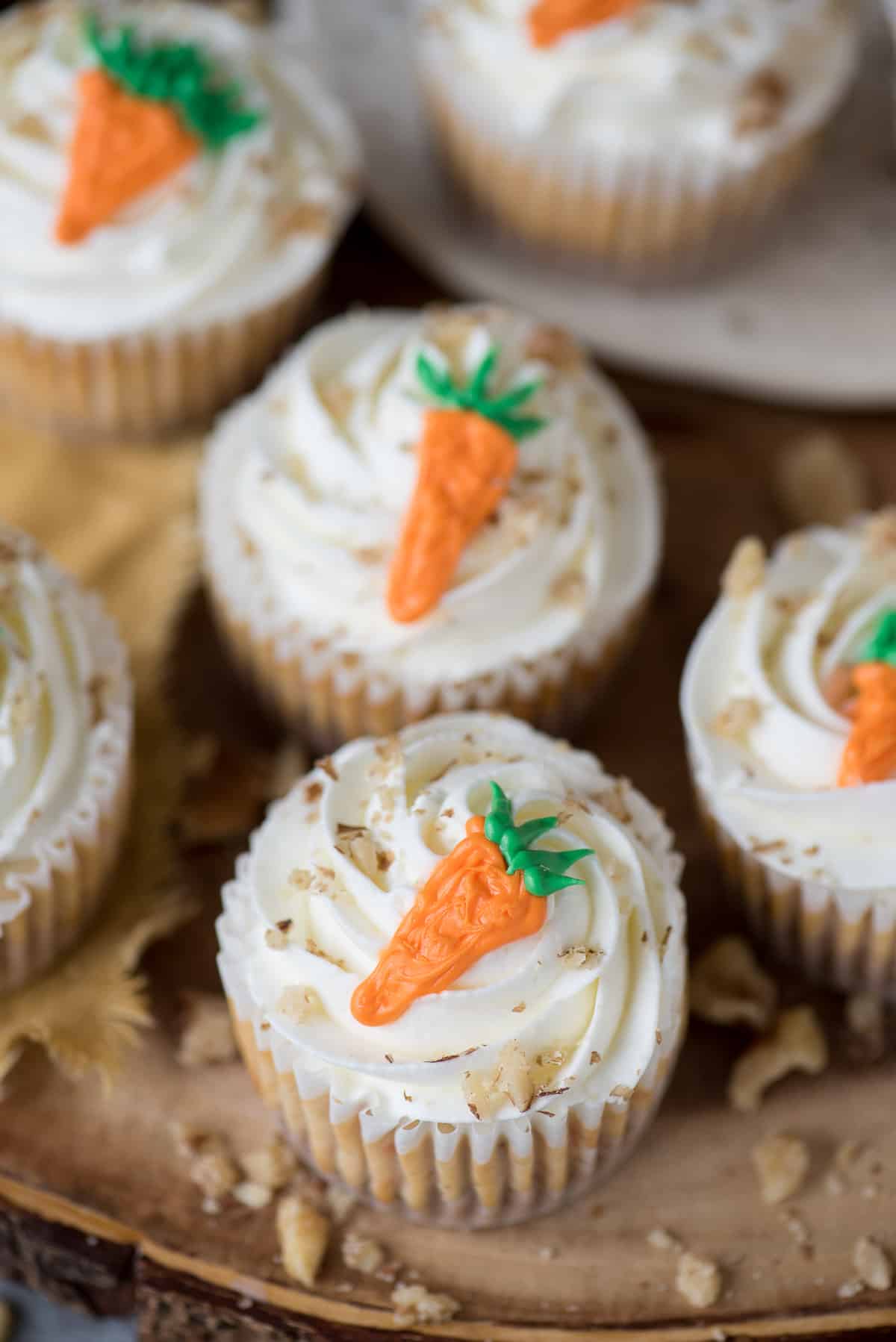 mini carrot cheesecakes with frosting carrot on top on wood background