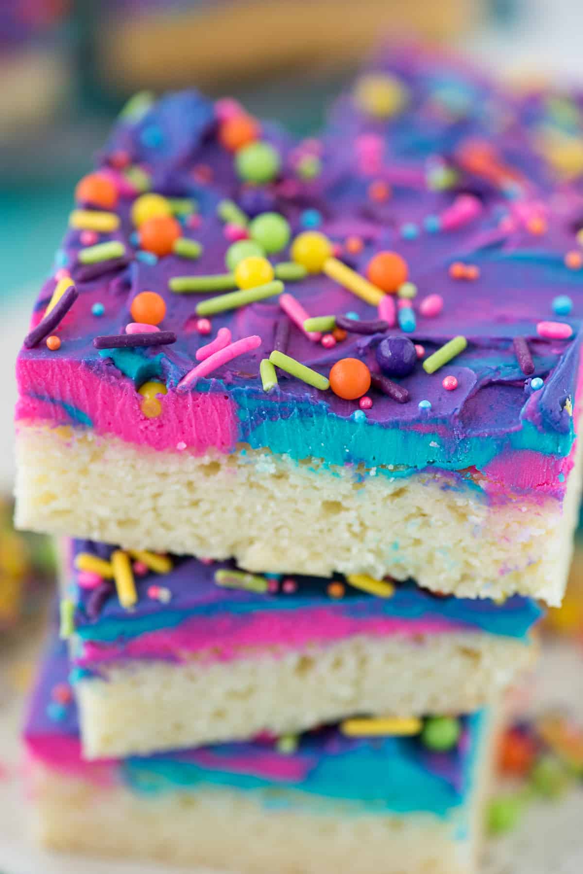 sugar cookie bars with tie dye pink purple and teal frosting with sprinkles