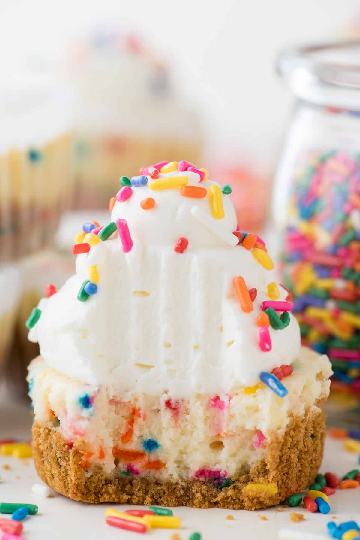 mini funfetti cheesecake with rainbow colored sprinkles on top with a bite taken out