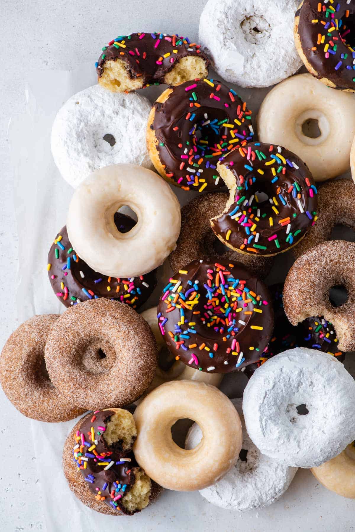 baked donuts with a variety of glazes arranged on white background