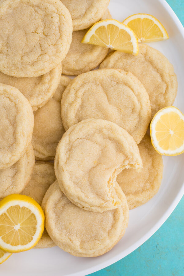 lemon sugar cookies with lemon slices on white plate on blue background