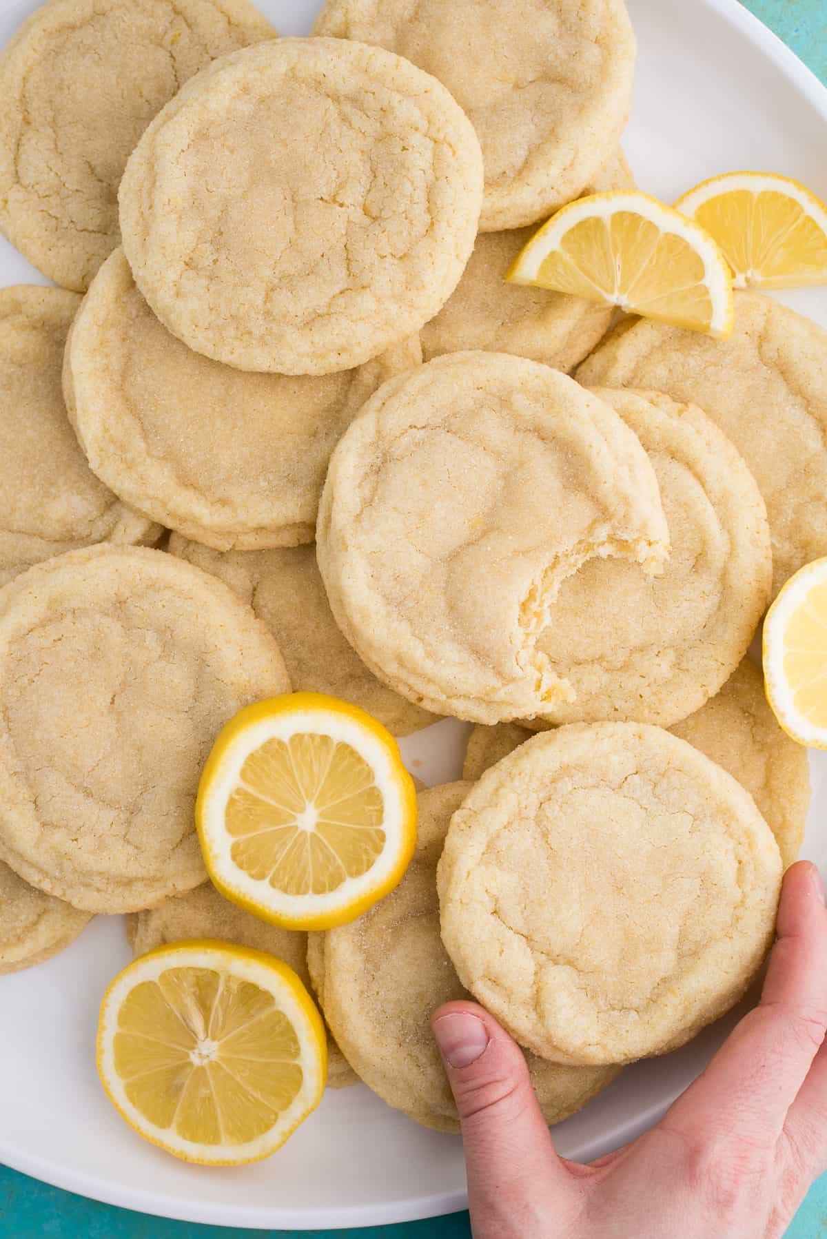 lemon sugar cookies with lemon slices on white plate on blue background