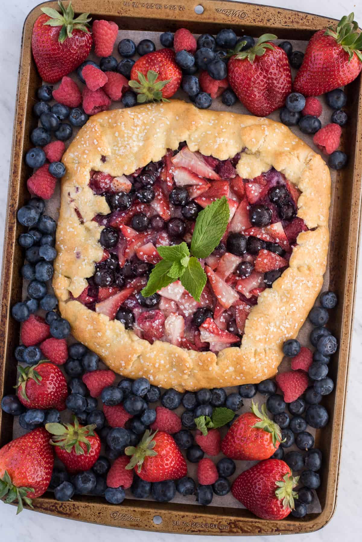 mixed berry galette with strawberries and blueberries on metal baking sheet