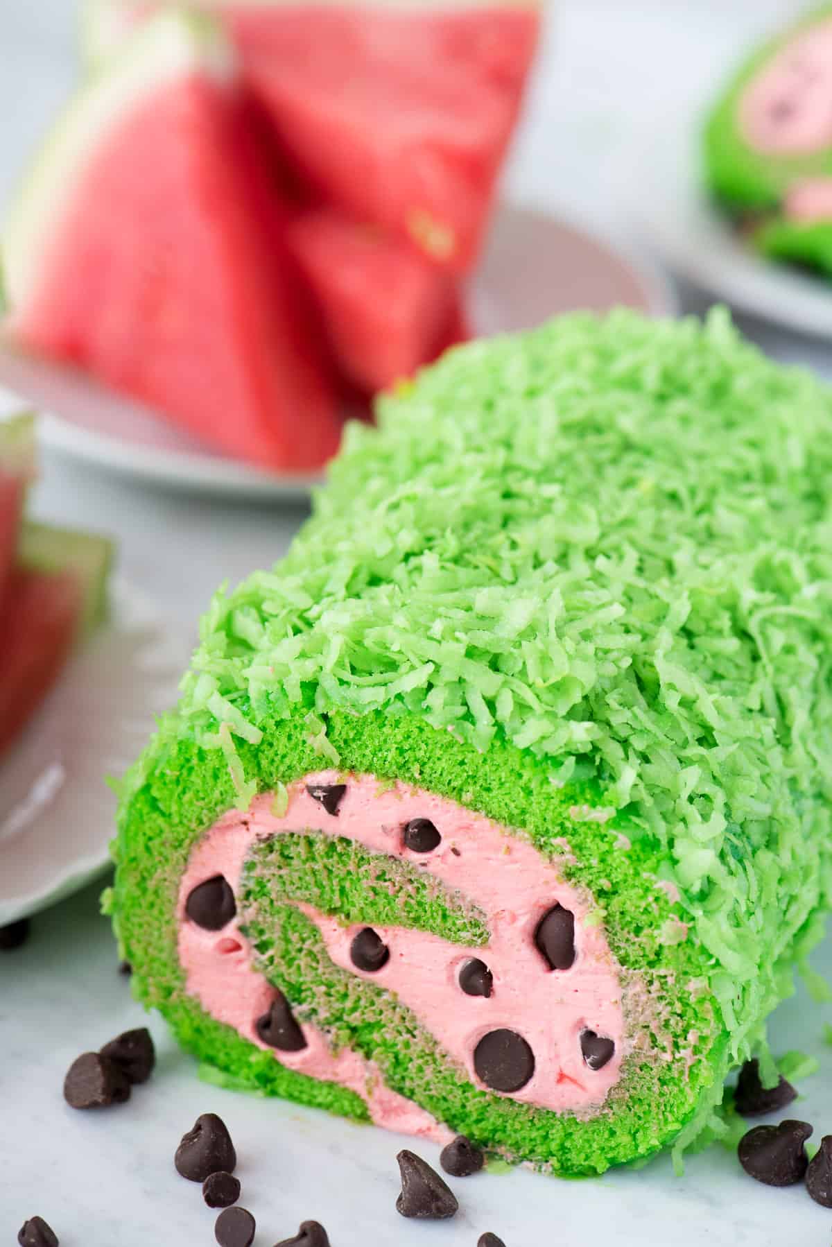 green cake roll with pink filling and chocolate chips to look like a watermelon cake roll