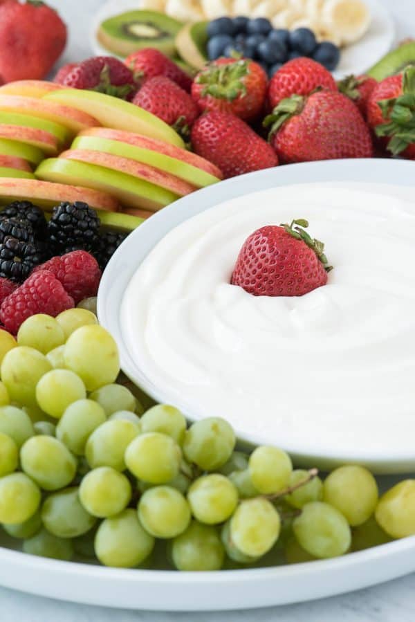 3 ingredient fruit dip! We love this creamy dip because there’s NO cream cheese! round platter filled with strawberries, apples, blackberries, raspberries and grapes with a bowl of white fruit dip