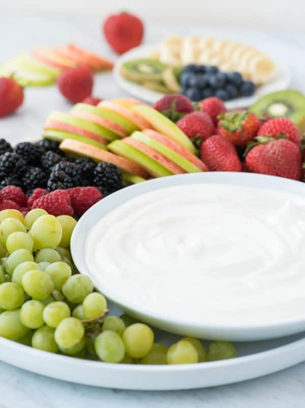 3 ingredient fruit dip! We love this creamy dip because there’s NO cream cheese! round platter filled with strawberries, apples, blackberries, raspberries and grapes with a bowl of white fruit dip