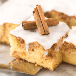 Square of honey bun cake topped with two cinnamon sticks