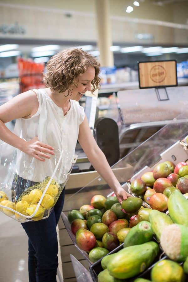 woman shopping for mango in a grocery store 