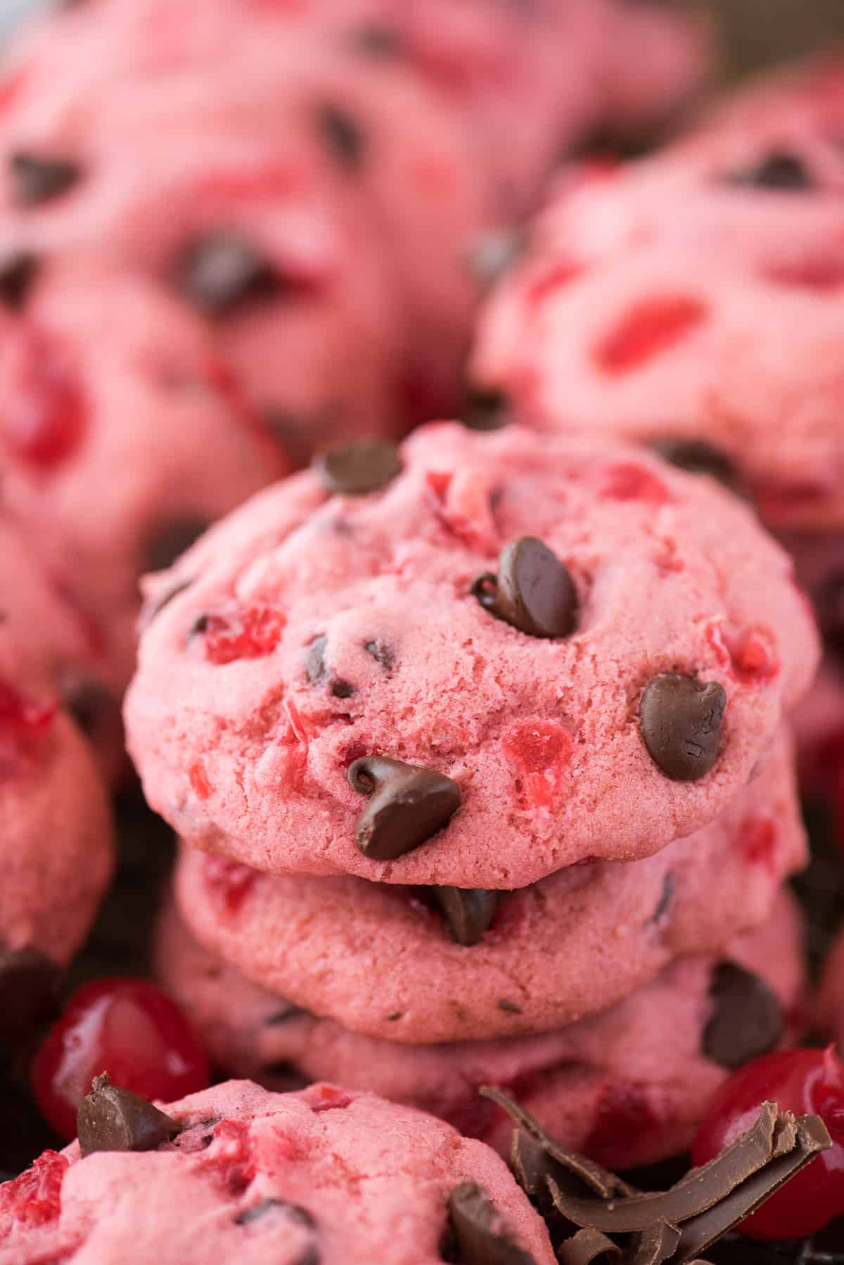 pink maraschino cherry chocolate chip cookies on baking sheet with cherries and chocolate chips