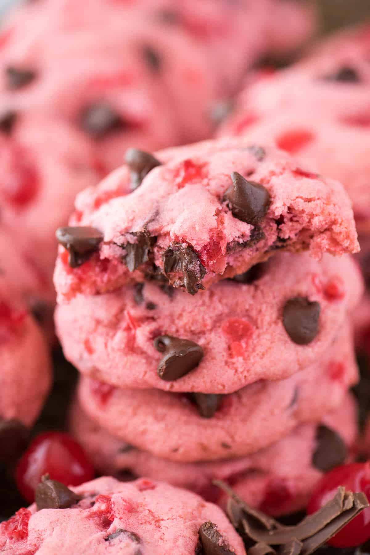 pink maraschino cherry chocolate chip cookies on baking sheet with cherries and chocolate chips