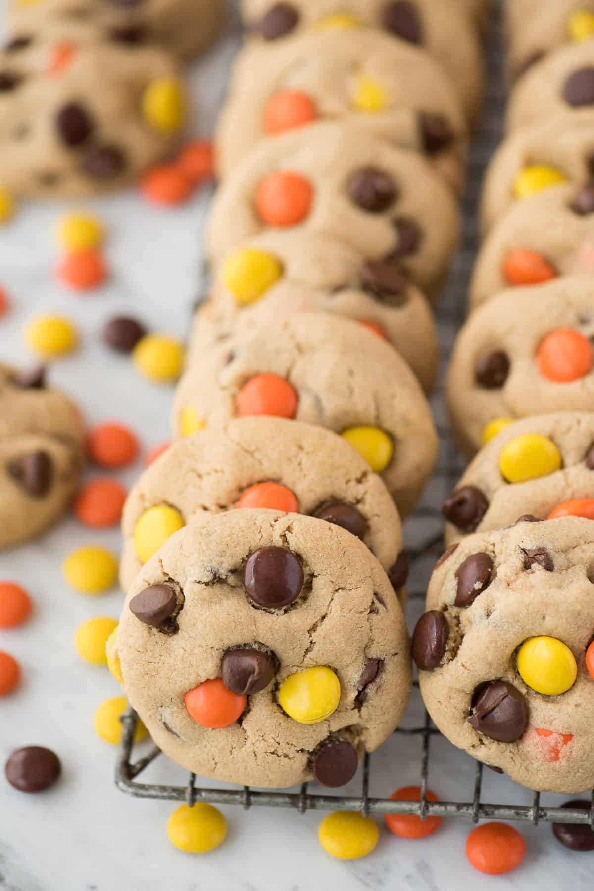 peanut butter cookies with reese's pieces candies and chocolate chips on white background