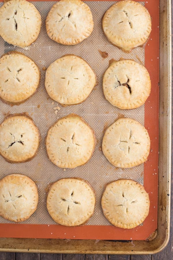 Homemade apple hand pies are a great apple dessert to make any time of the year. Watch the quick step by step video to learn how to make these mini apple pies. #applehandpies #handpies #applepie #minipie apple hand pies on a silicone lined baking sheet