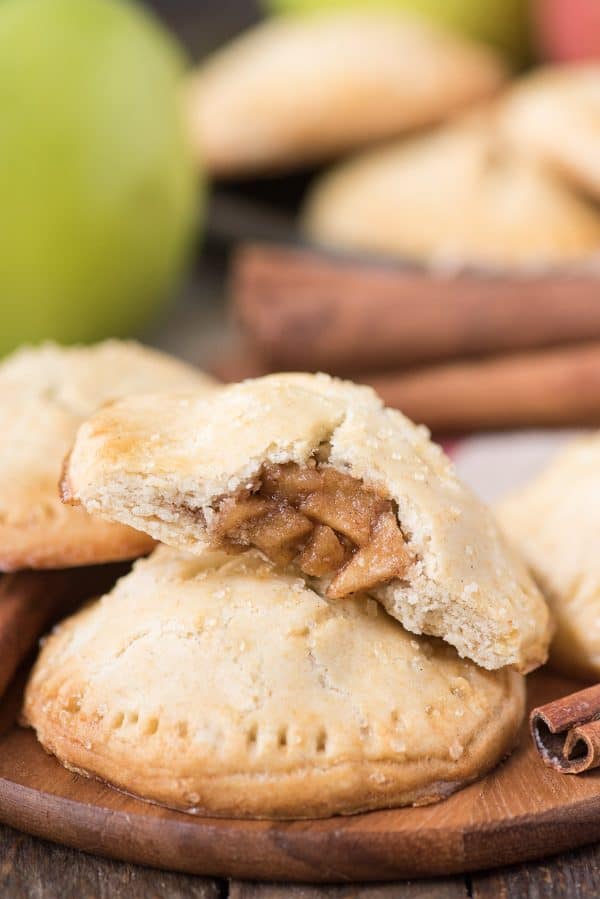 Homemade apple hand pies are a great apple dessert to make any time of the year. Watch the quick step by step video to learn how to make these mini apple pies. #applehandpies #handpies #applepie #minipie apple hand pies on wood background with green apple in the background