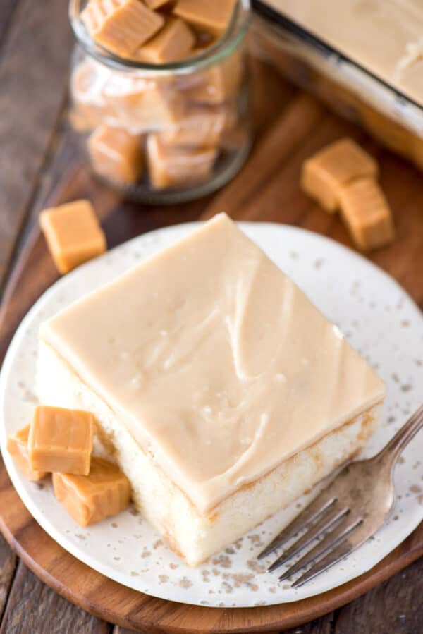 slice of caramel cake on white plate on wood background