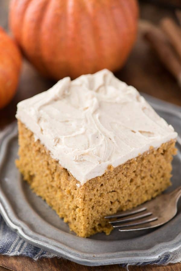 Take a spice cake mix and turn it into a doctored up pumpkin cake! With directions for how to make doctored up pumpkin cake or cupcakes, this is our family’s new favorite pumpkin cake! slice of doctored up pumpkin cake on metal plate with pumpkin in background
