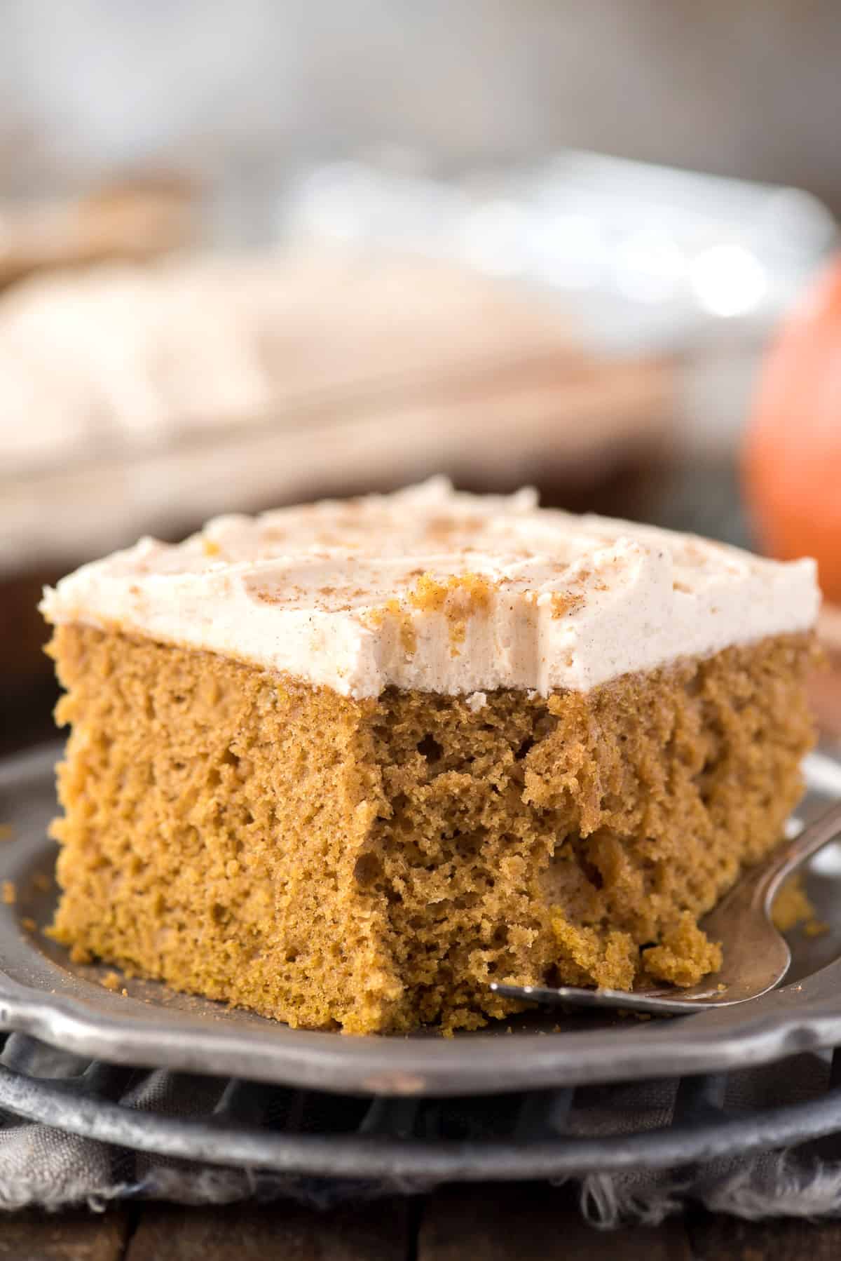 slice of pumpkin cake on metal plate with pumpkin in background
