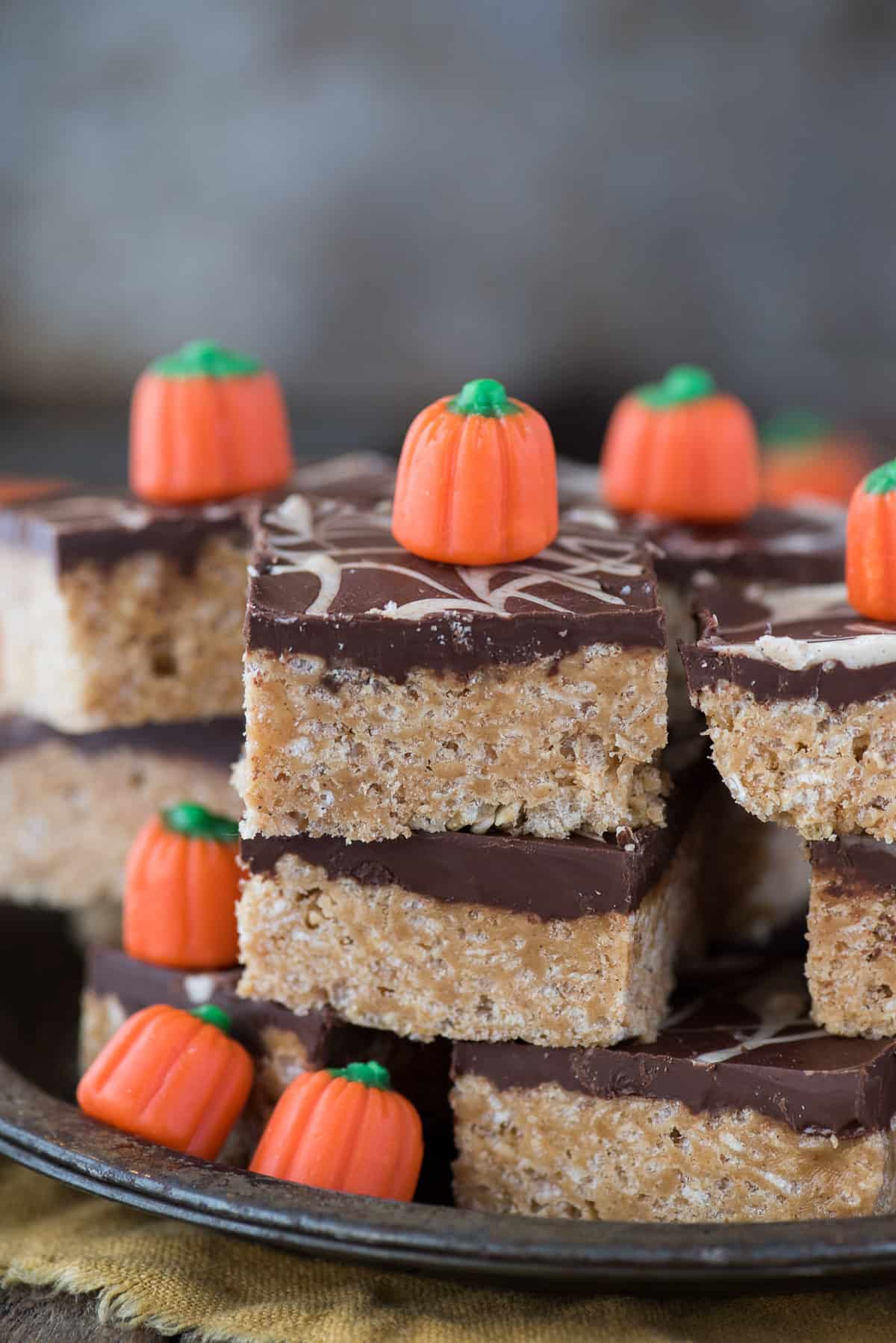 pumpkin spice scotcheroo bars stacked in a pile with candy corn pumpkins on top