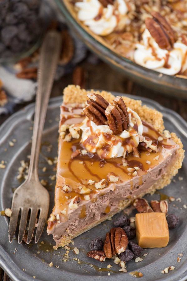Easy to make classic turtle pie! This no bake turtle pie has a 4 ingredient filling that is creamy and rich. Add pecans, caramel and chocolate sauce and you have a quick homemade turtle pie! slice of turtle pie with chocolate filling, chopped pecans and caramel drizzle on metal plate