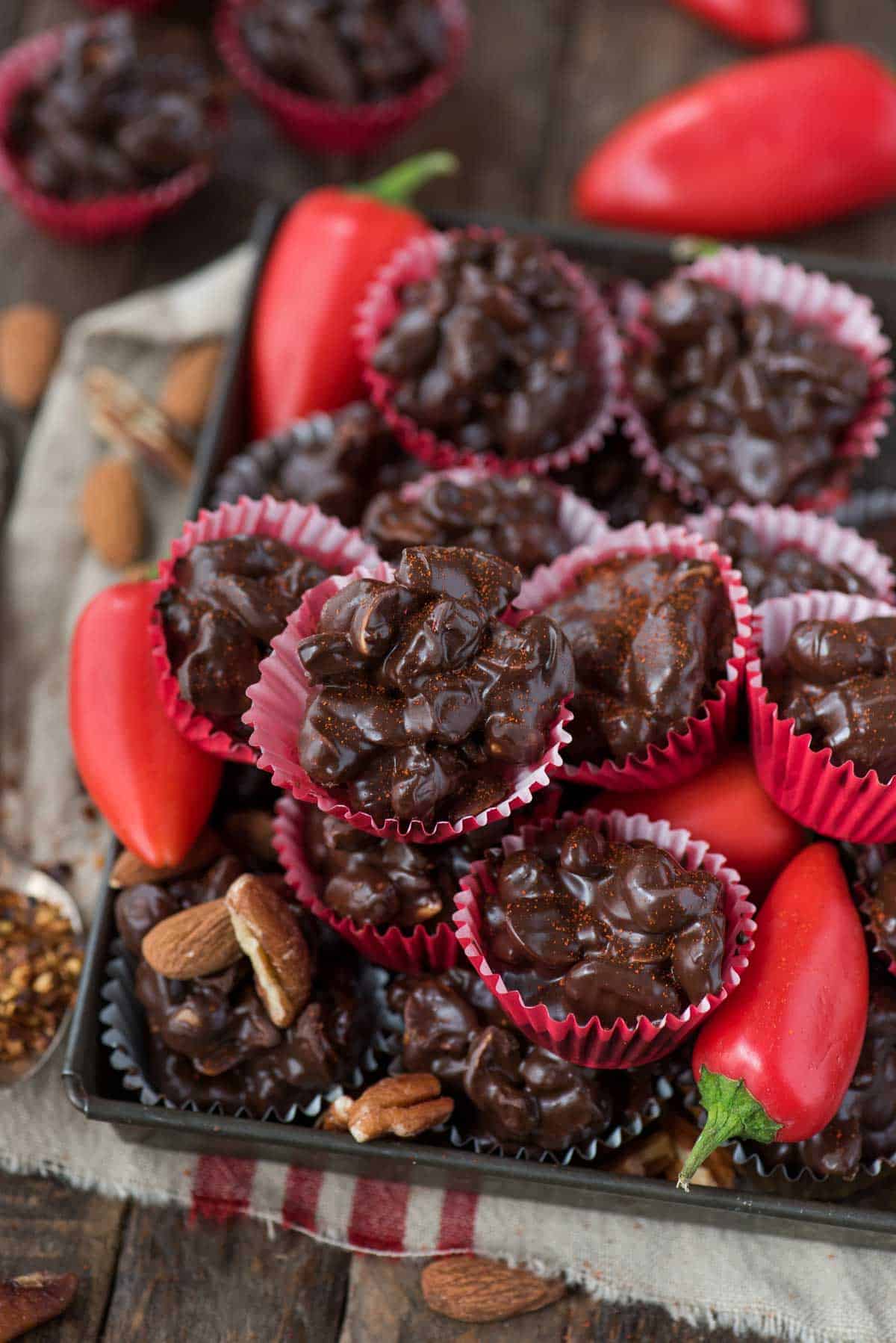 dark chocolate cayenne nut clusters in red mini muffin paper cups on wood background