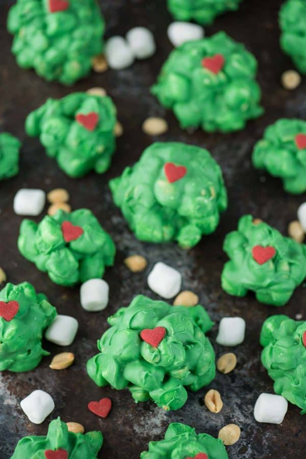 Easy to make Grinch peanut marshmallow candy clusters. These are a family favorite to make each holiday season. Make this grinch candy while watching The Grinch! peanut marshmallow clusters coated in green chocolate with a red candy heart for grinch clusters!