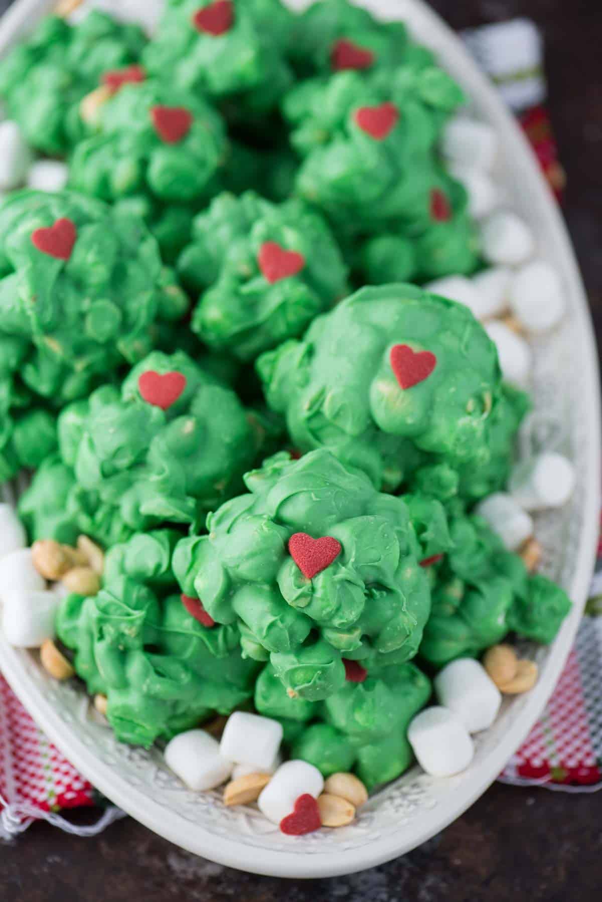 peanut marshmallow clusters coated in green chocolate with a red candy heart for grinch clusters!