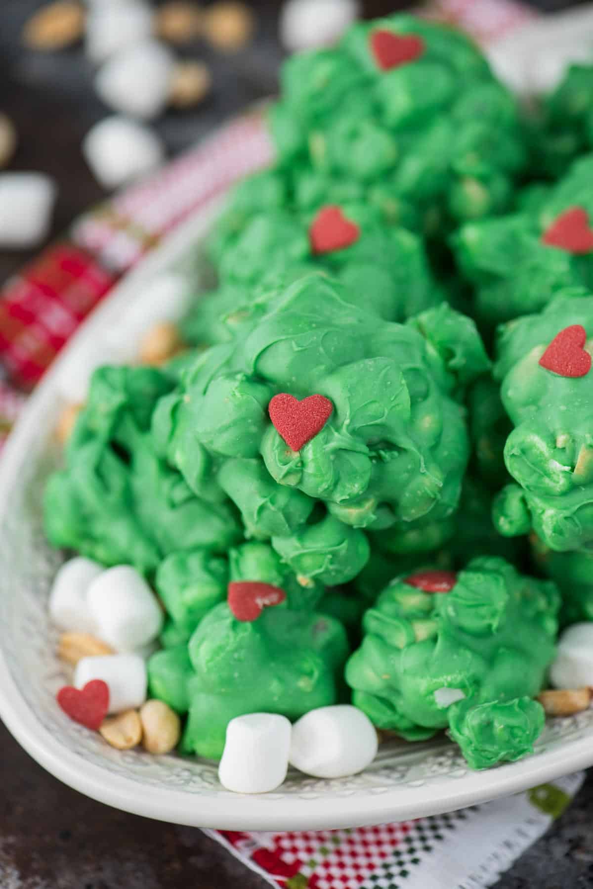 peanut marshmallow clusters coated in green chocolate with a red candy heart for grinch clusters!