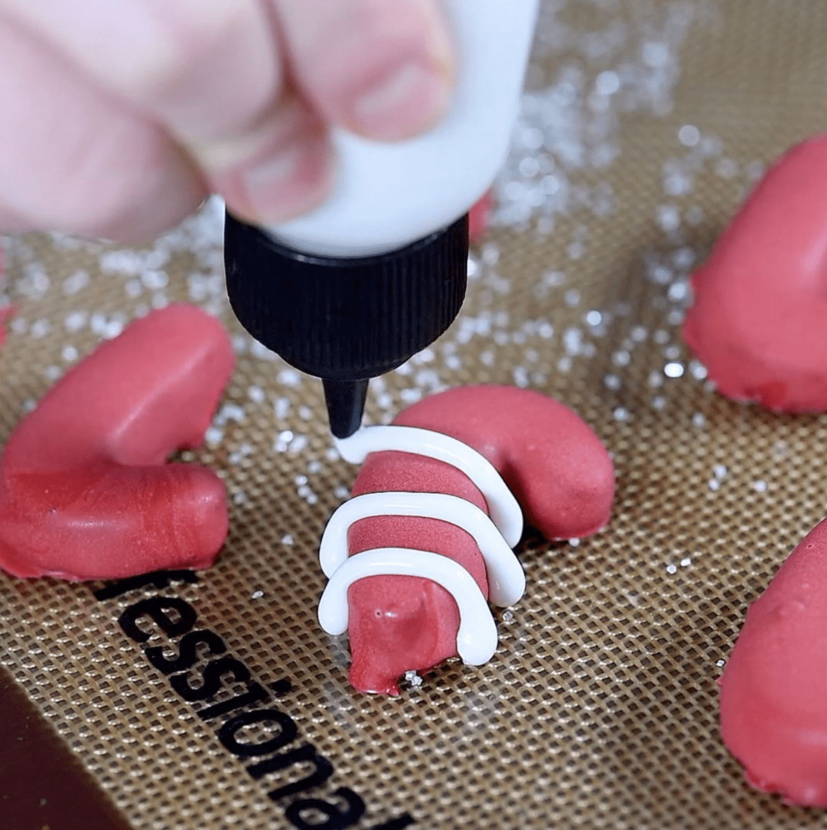 white frosting in squeeze bottle, piping over candy cane to create stripes