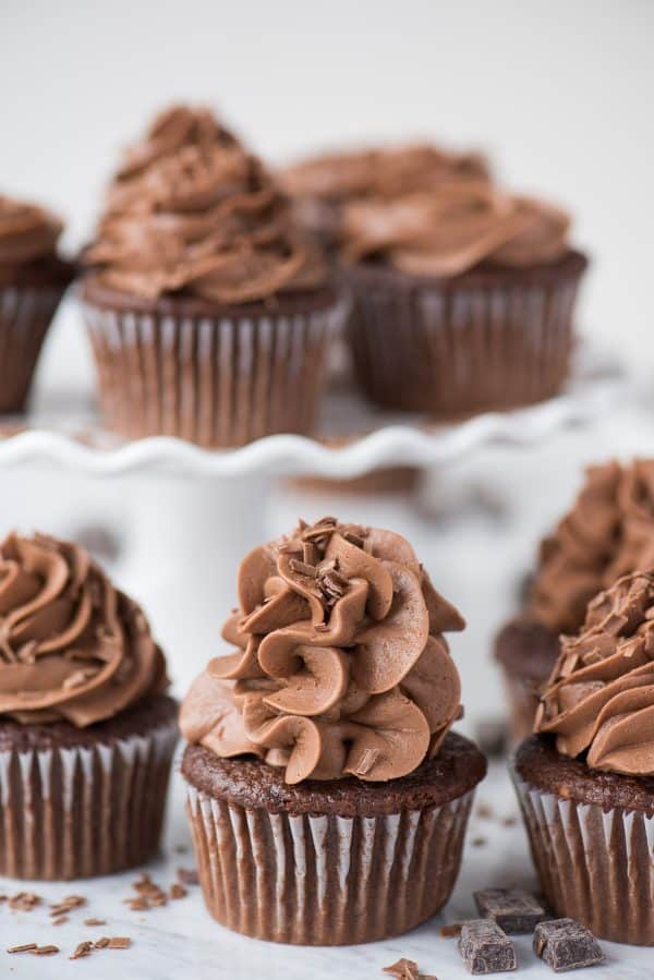Bakery style “doctored up” chocolate cupcakes! This is an easy, one bowl chocolate cake mix cupcake recipe without pudding or coffee. #chocolate #cupcakes #cakemix #cakemixcupcakes #doctoredupcake #easycupcakes chocolate cupcakes with chocolate frosting on white background