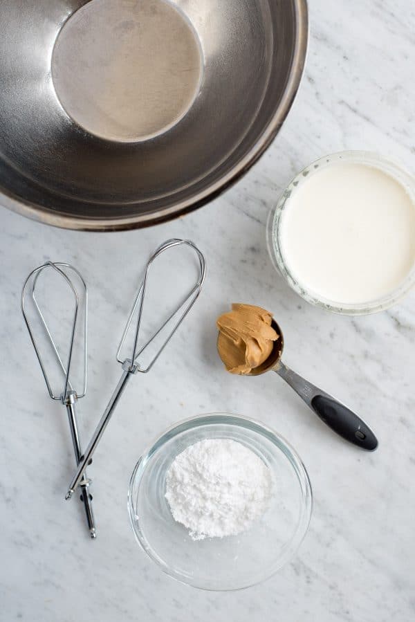 Easy to make peanut butter whipped cream frosting! This peanut butter whipped cream makes a great frosting for cake & cupcakes. Includes recipe note for how to make keto peanut butter whipped cream. metal mixing bowl, beaters, heavy cream, peanut butter and powdered sugar