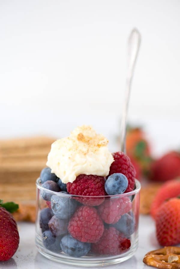 How to make stabilized cheesecake flavored whipped cream that you can use on cake, cupcakes, pies, and as fruit dip! Imagine this cheesecake flavored whipped cream on strawberry pie! #whippedcream #flavoredwhippedcream #cheesecakewhippedcream cheesecake flavored whipped cream on top of a bowl of raspberries and blueberries