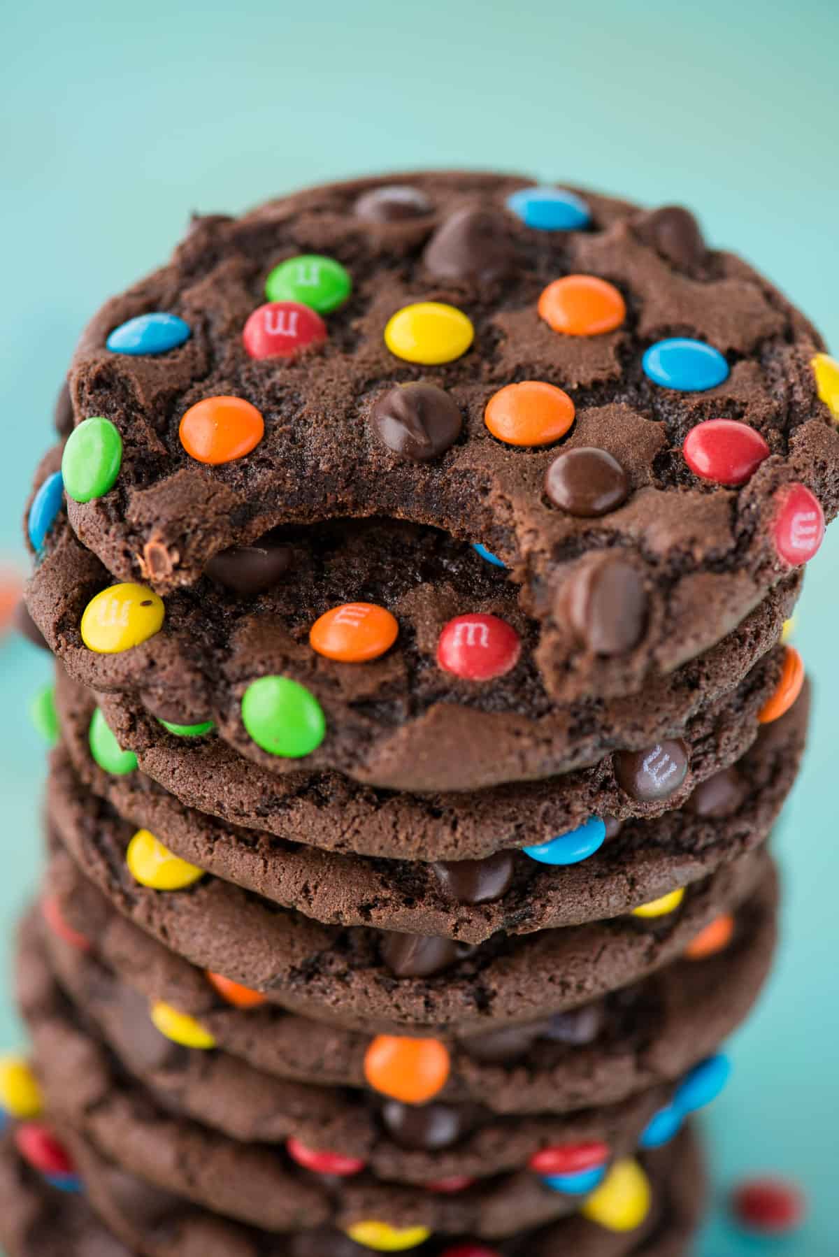 double chocolate chip cookies with m&ms and chocolate chips stacked in a pile