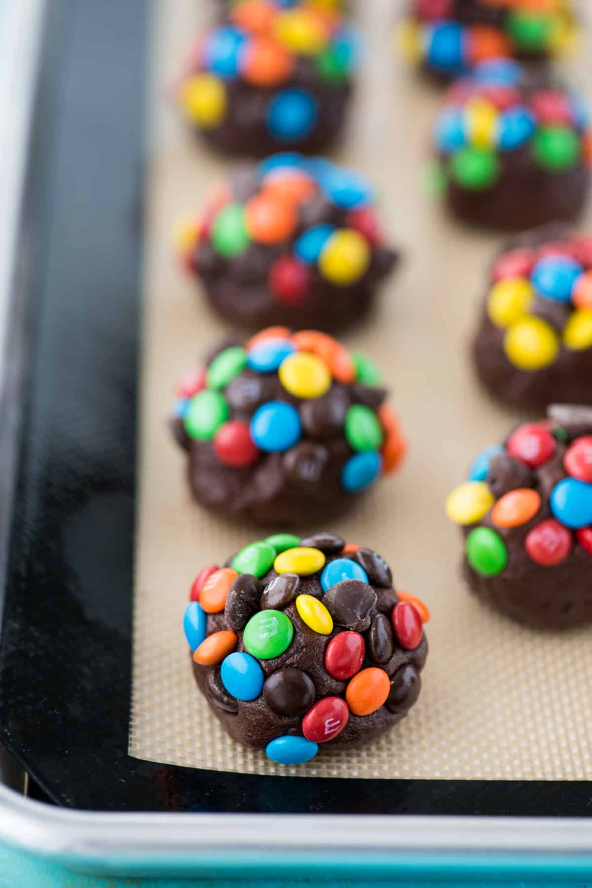 double chocolate chip cookie dough balls with m&ms and chocolate chips on silicone baking mat