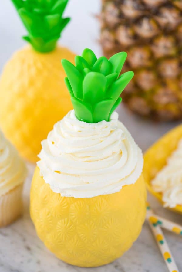 Easy to make 3 ingredient pineapple whipped cream frosting! This pineapple whipped cream makes a great frosting for cake & cupcakes. Use it as a whipped topping on tropical drinks too! #whippedcream #pineapplefrosting #pineapplewhippedcream pineapple whipped cream piped inside plastic pineapple cup