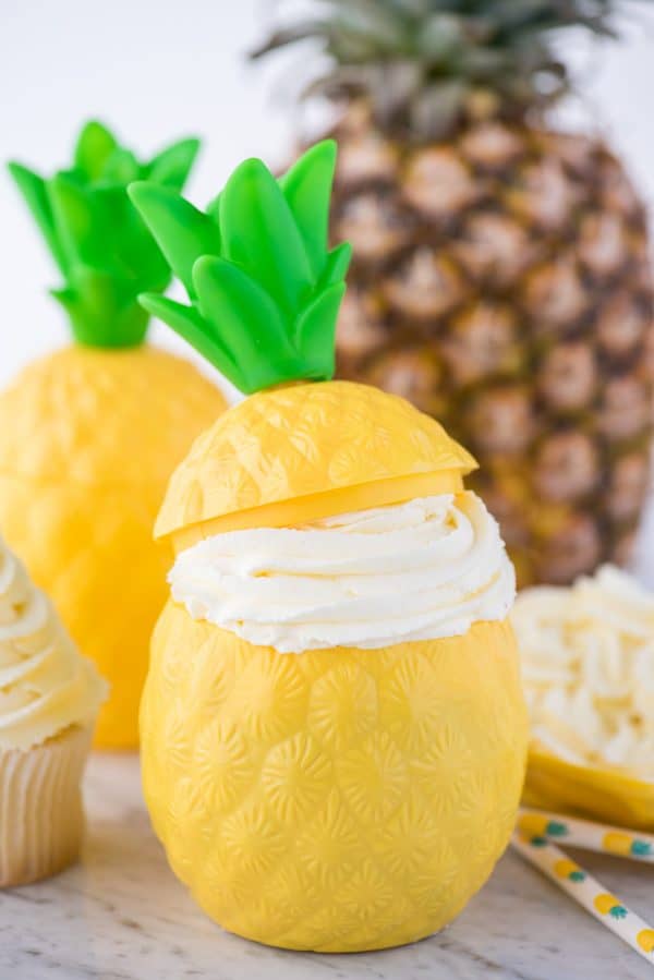 Easy to make 3 ingredient pineapple whipped cream frosting! This pineapple whipped cream makes a great frosting for cake & cupcakes. Use it as a whipped topping on tropical drinks too! #whippedcream #pineapplefrosting #pineapplewhippedcream pineapple whipped cream in plastic pineapple cup