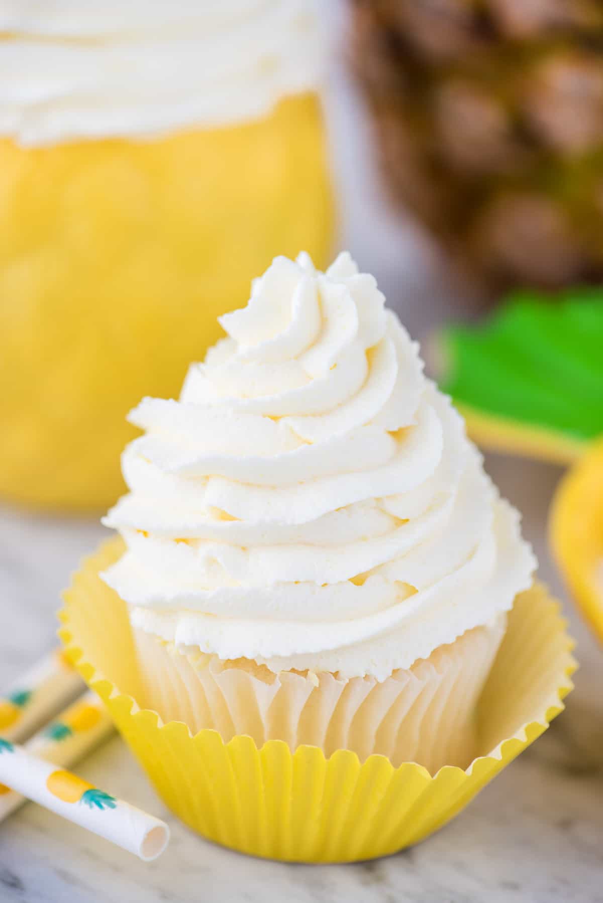 pineapple whipped cream frosting piped onto white cupcake