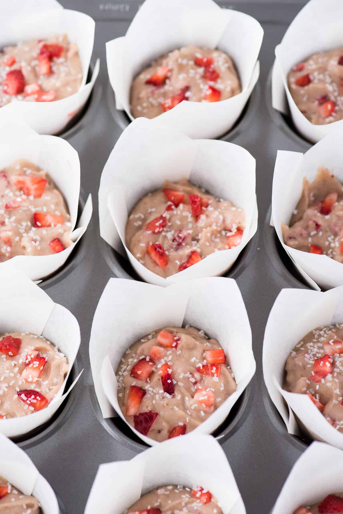 strawberry banana muffins in white parchment paper liners in muffin pan