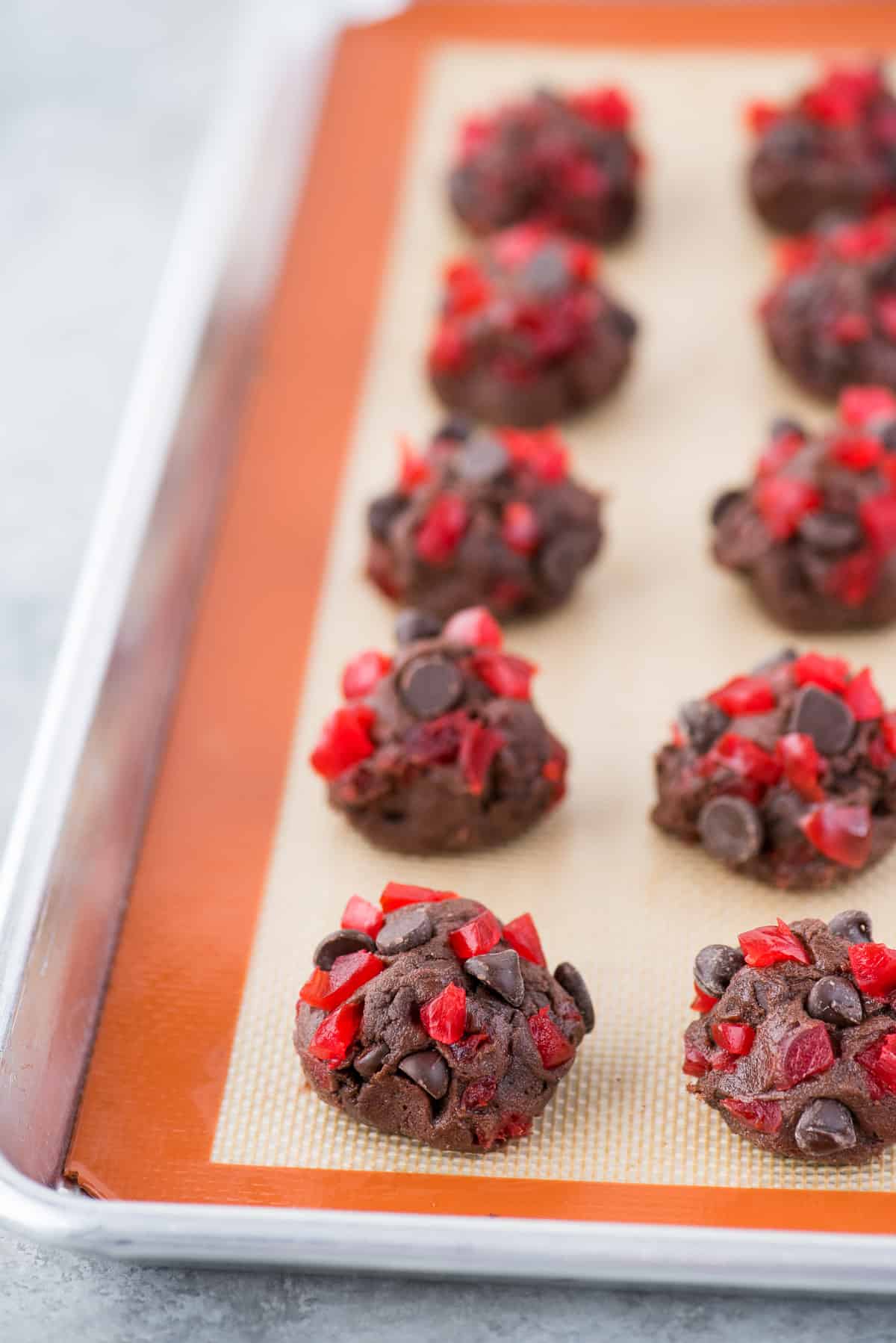 black forest cookie dough balls with maraschino cherries and chocolate chips on silicone baking mat