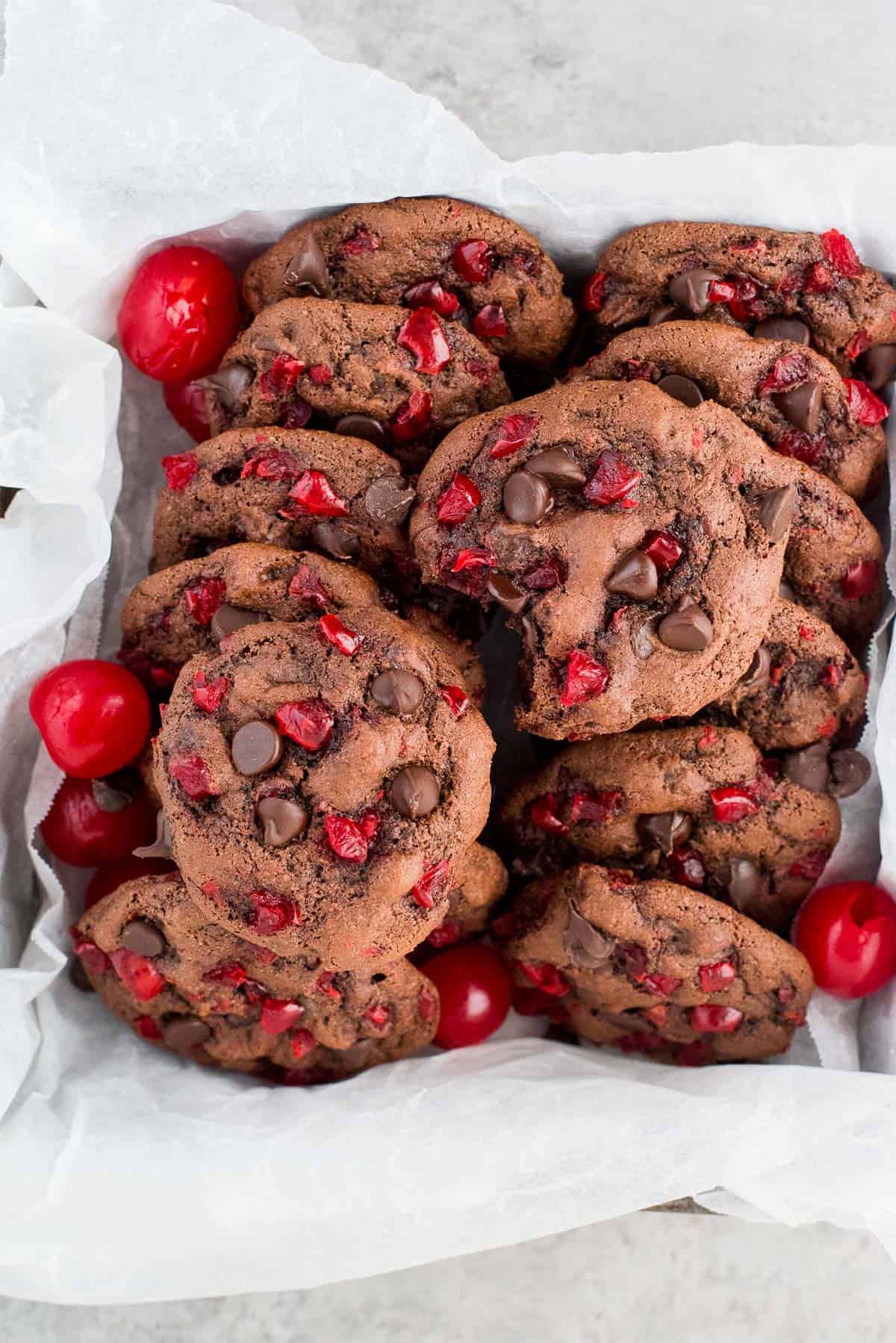 black forest cookies with maraschino cherries and chocolate chips lined in a container with white paper