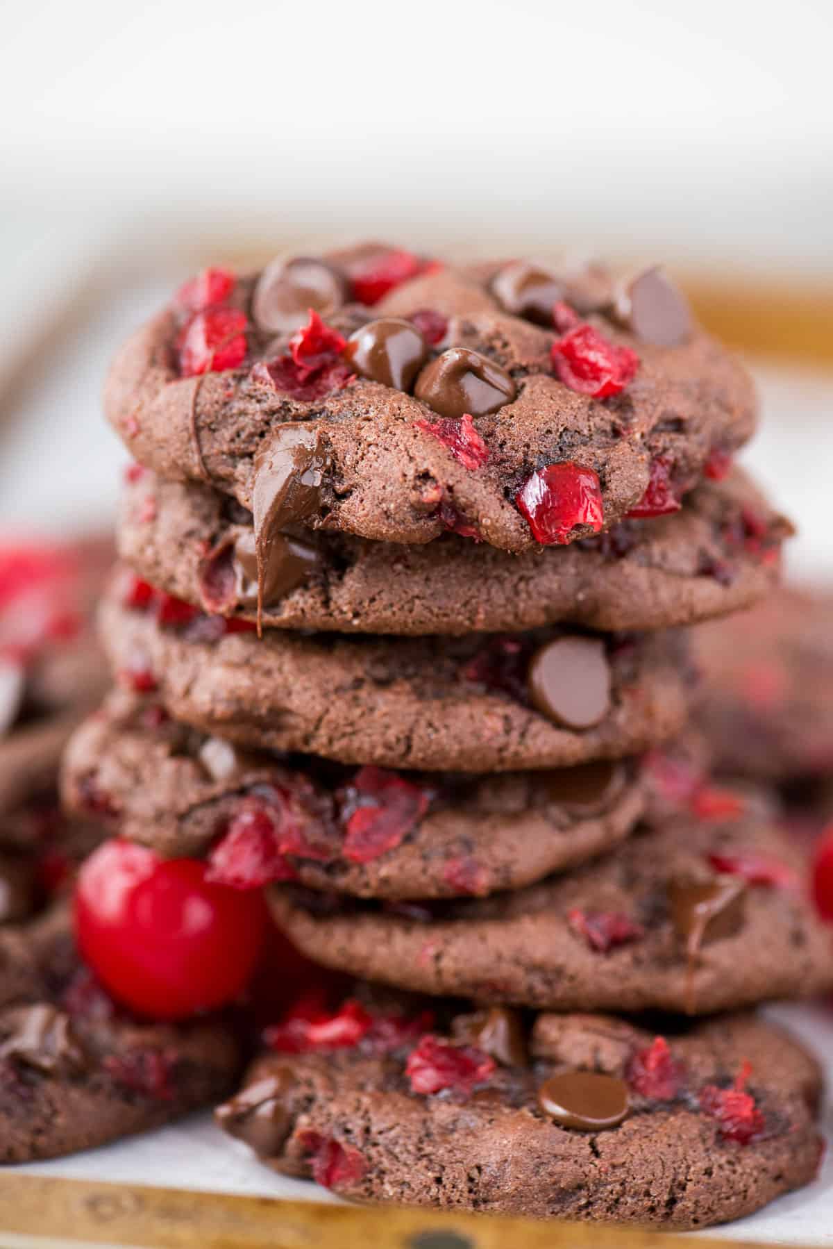 black forest cookies with maraschino cherries and chocolate chips stacked in a pile on metal baking sheet