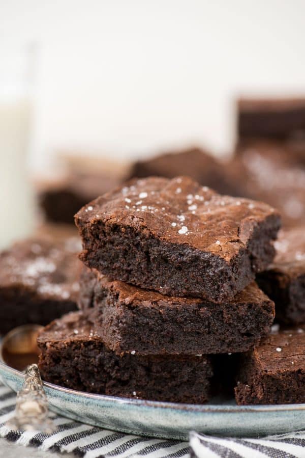 homemade brownies stacked in a tower on light blue plate with white background